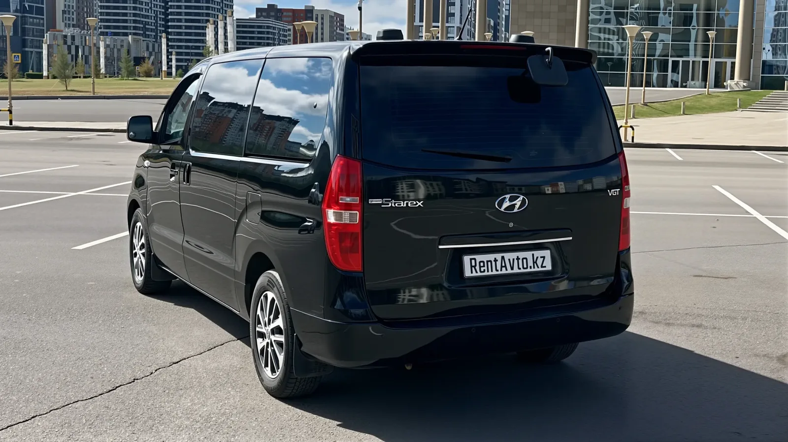 Hyundai Grand Starex на 10 мест показан сзади, видны большие боковые окна во время развозки сотрудников