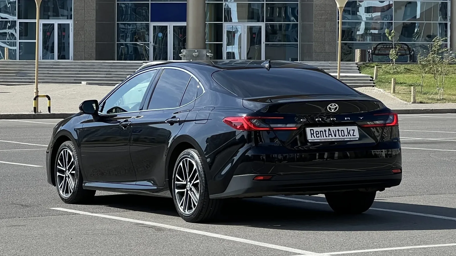 Чёрная Toyota Camry 80 снята сзади на ровной площадке в Астане, автомобиль заблаговременно готовится для сопровождения гостей