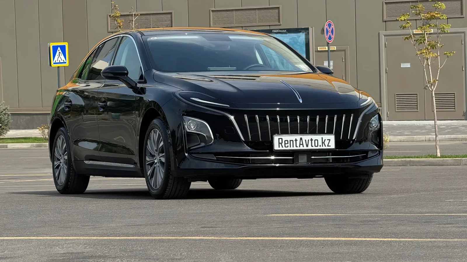 Чёрный электроседан Hongqi E-QM5 сфотографирован спереди на городской площадке в Астане, его часто оформляют в аренду с водителем для деловых поездок
