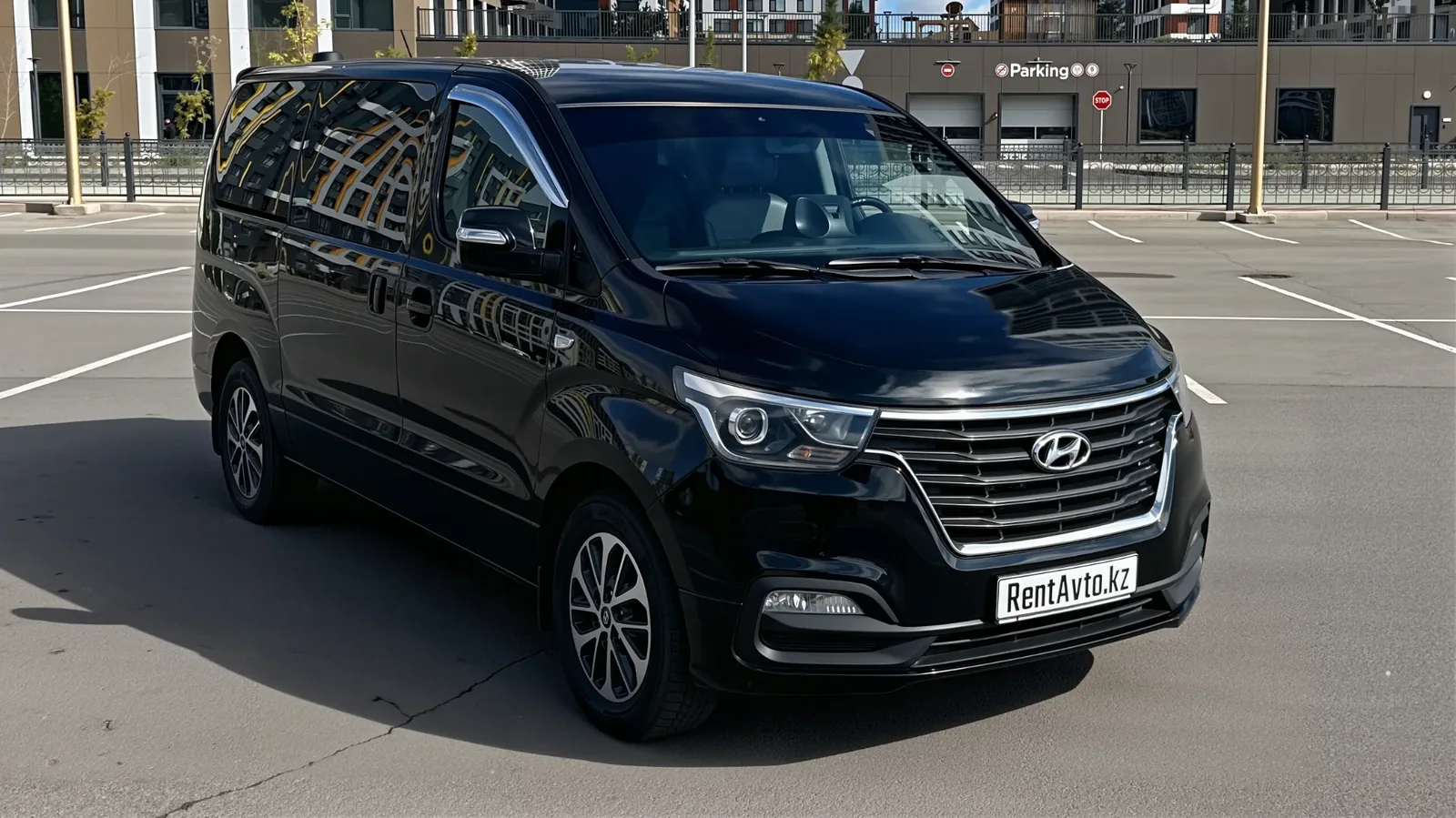 Чёрный Hyundai Grand Starex на 10 мест стоит на парковке возле деловых зданий в Астане, его берут в аренду для поездок небольшой группой