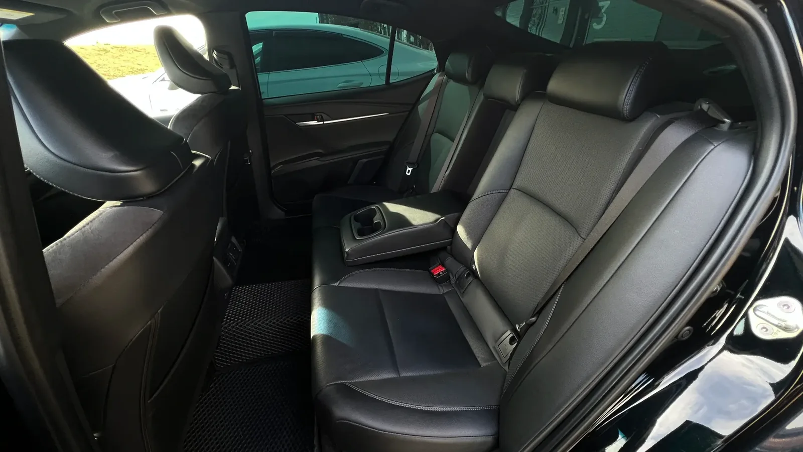 Задний ряд Toyota Camry 80 с откинутым подлокотником на трёх пассажиров, такой салон часто выбирают для трансферов между аэропортом и отелем