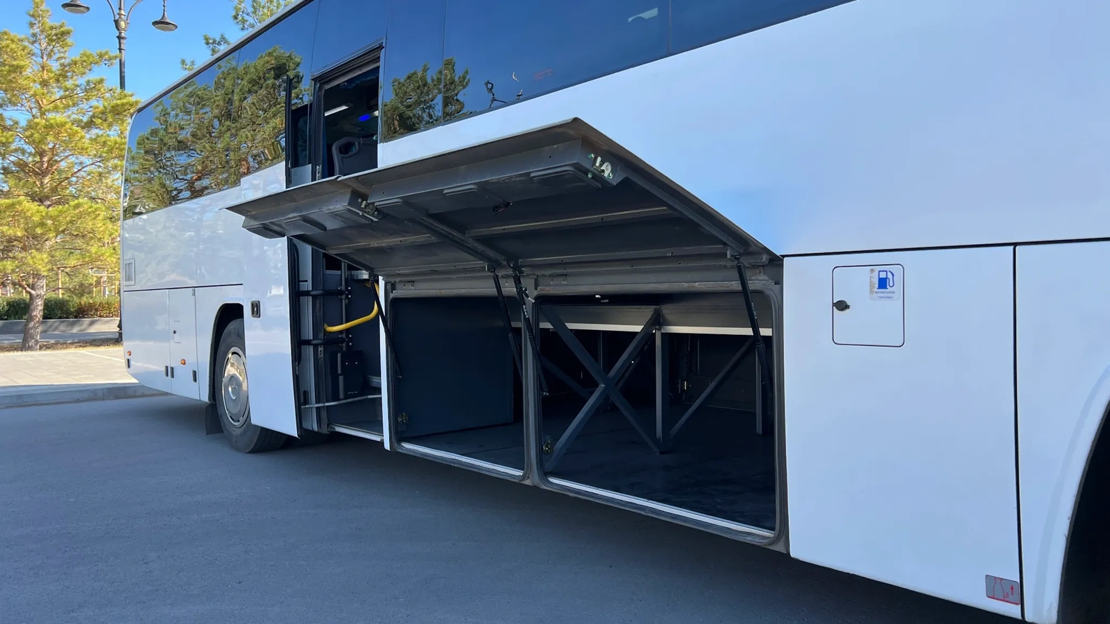 Белый автобус Higer на 54 места снят сбоку на открытой площадке, его используют для обслуживания туристических групп