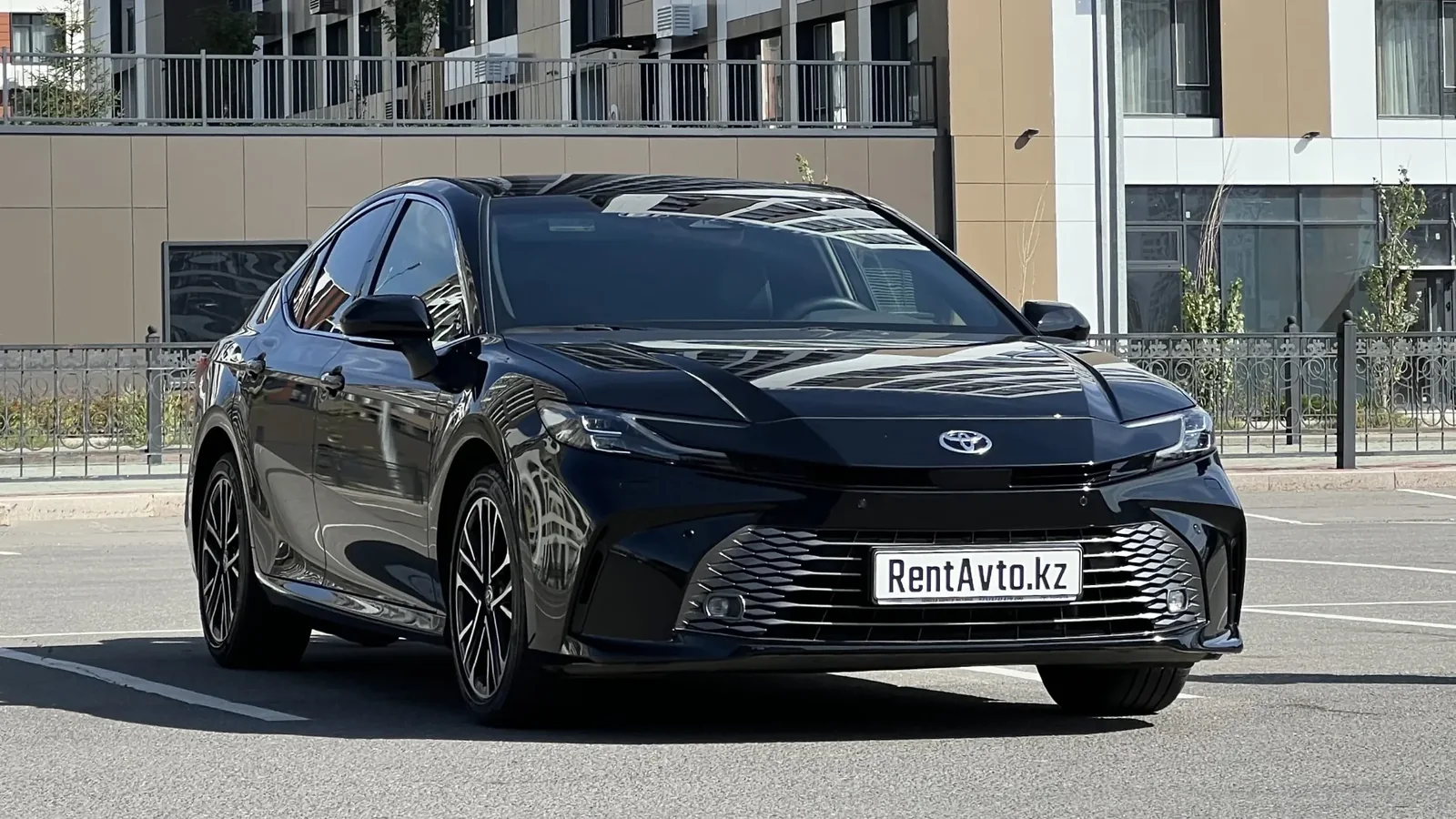 Чёрная Toyota Camry 80 спереди на фоне офисных зданий, седан для комфортных поездок по городу
