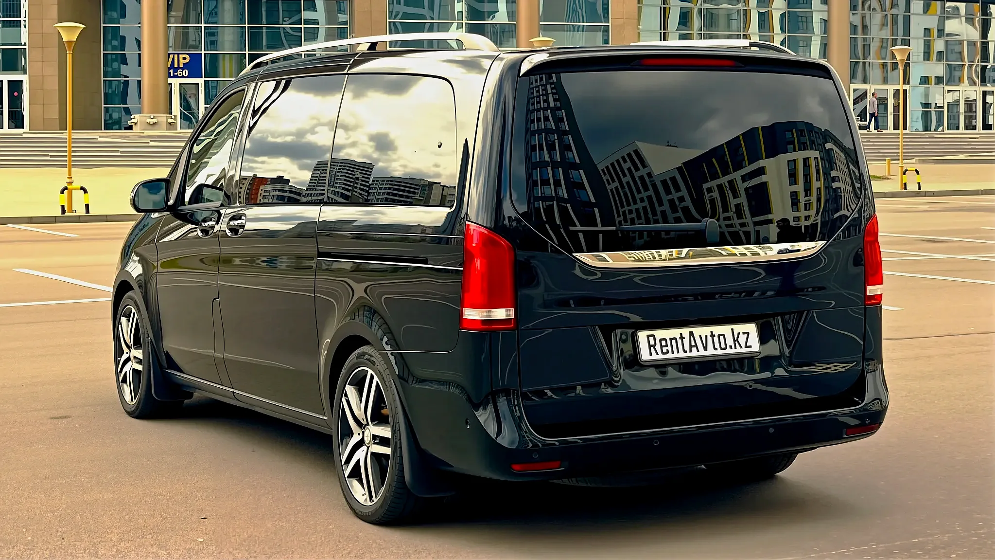 Премиальный Mercedes V-Class с видом заднего силуэта стоящего у аэропорта на трансфере