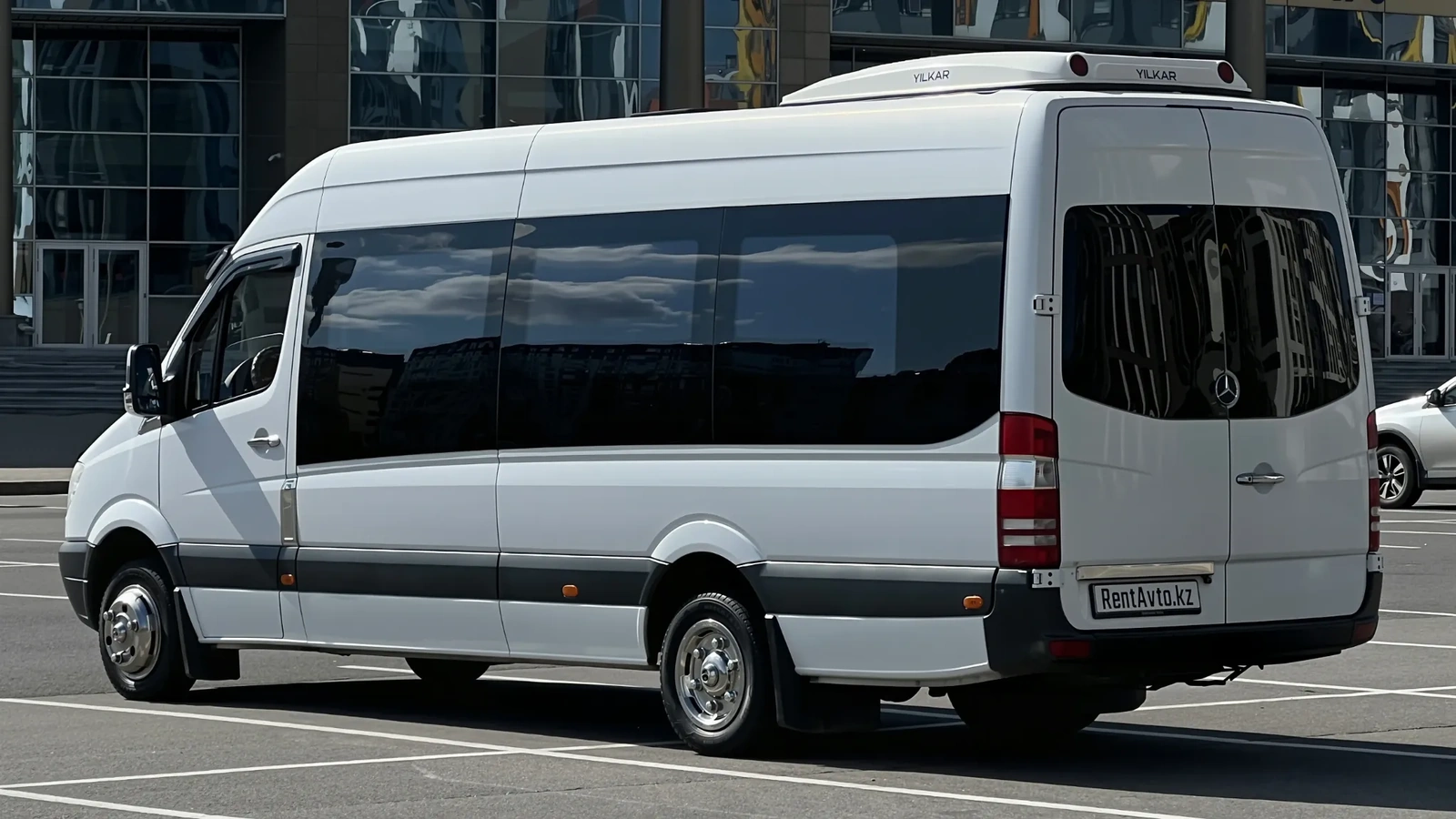 Белый Mercedes-Benz Sprinter на 20 мест в боковом ракурсе на городской улице Астаны перед работой в суточном режиме