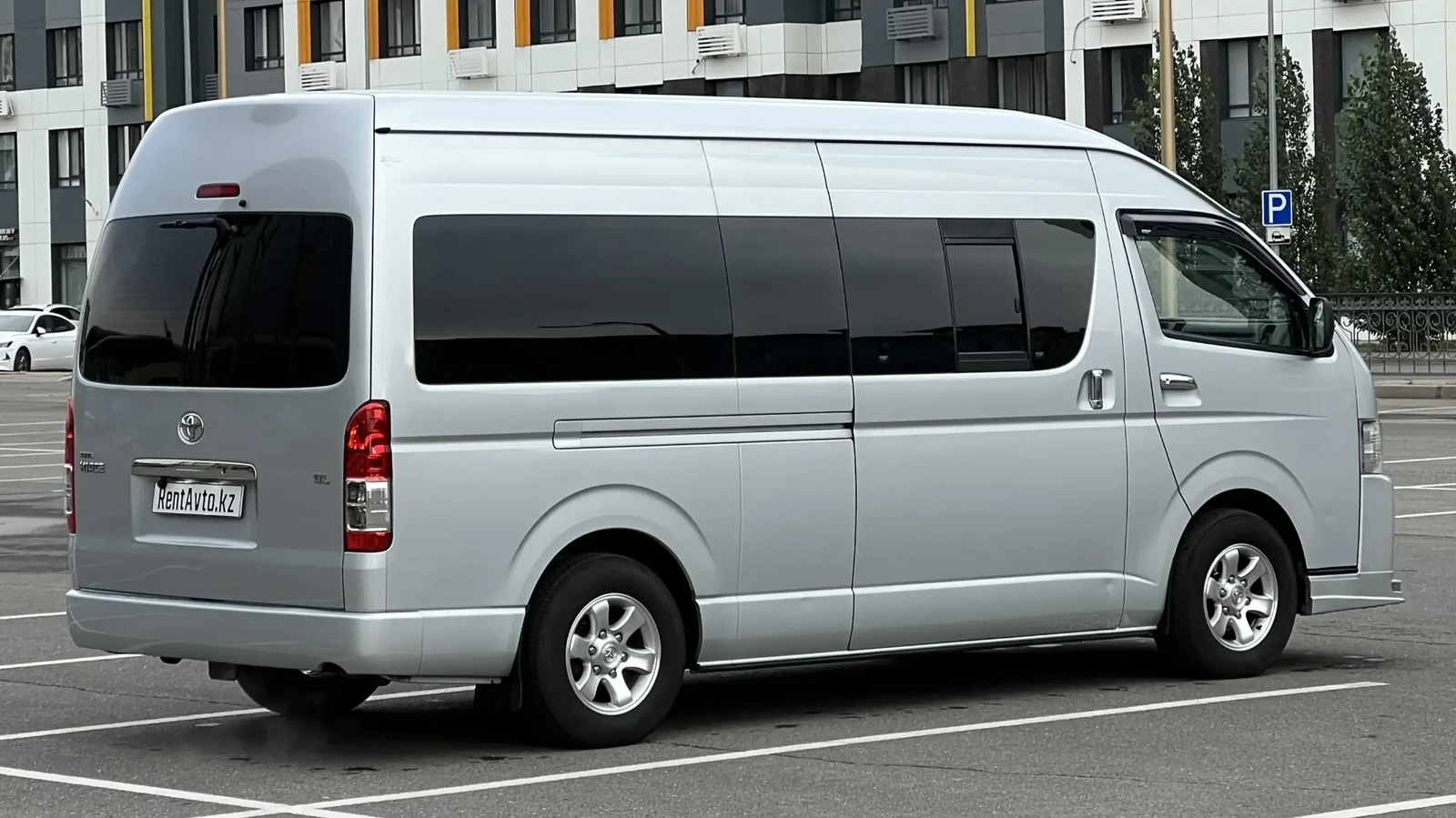 Серебристый Hiace на 12 мест в боковом ракурсе на улице города