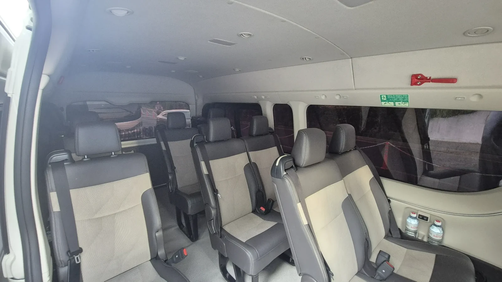 Белый Toyota Hiace на 9 мест, снятый спереди возле городского комплекса