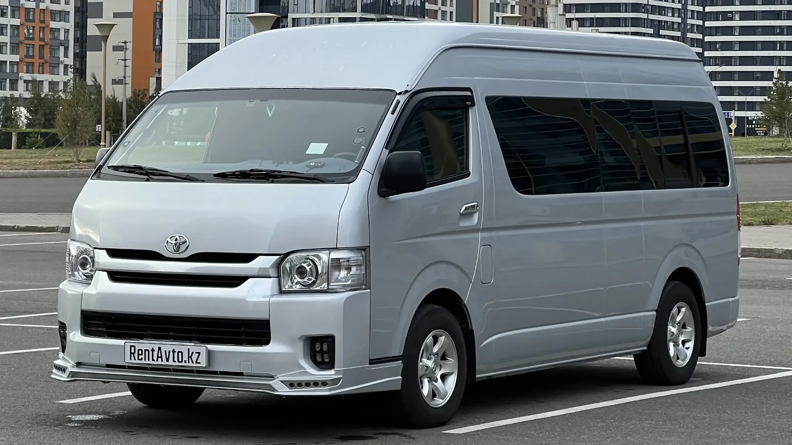 Серебристый Hiace на 12 мест в боковом ракурсе на улице города