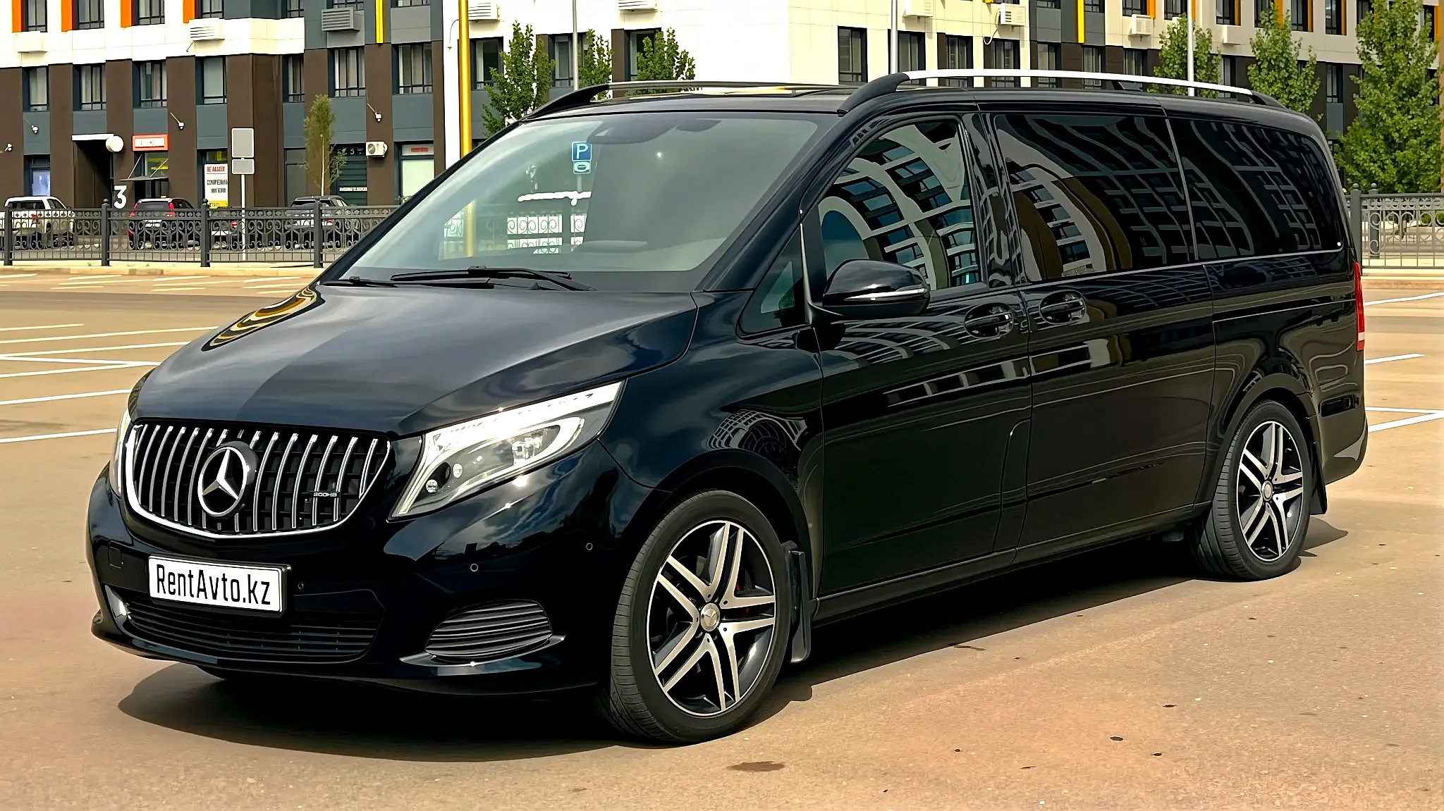 Чёрный Mercedes-Benz V-Class с фирменной решёткой радиатора припаркован на открытой площадке