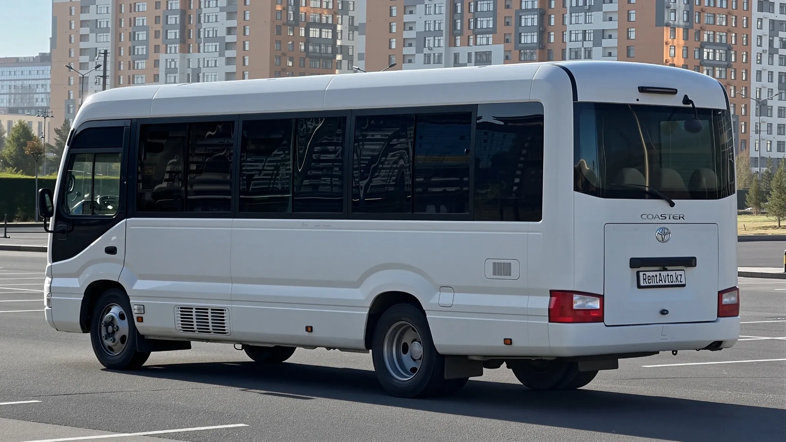 Автобус Toyota Coaster стоит на асфальтовой площадке, его часто выбирают для кортких передвижений с водителем