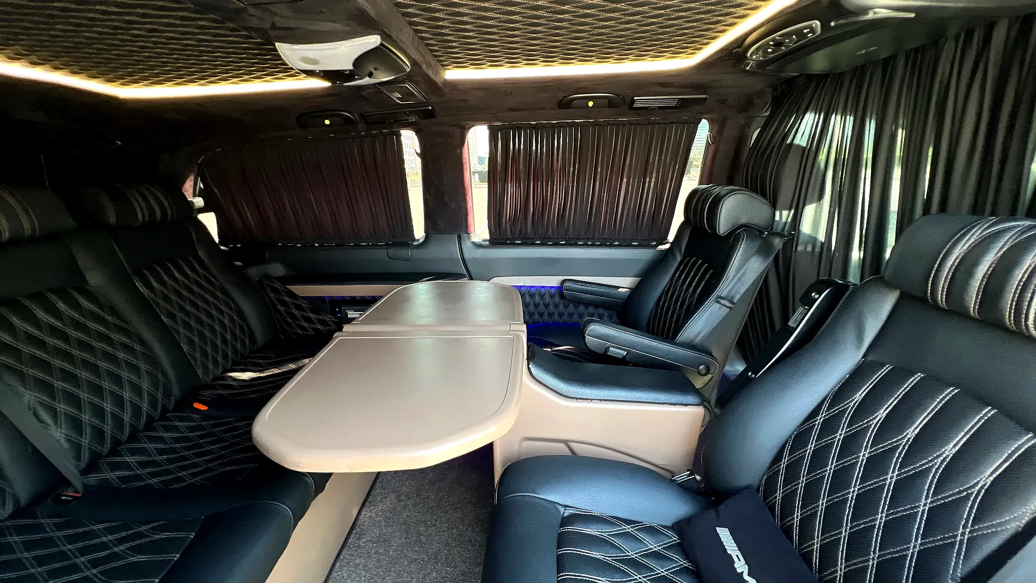 Небольшой стол внутри Mercedes-Benz Viano с кожаными креслами вокруг, подходящий для встречи гостей на мероприятиях