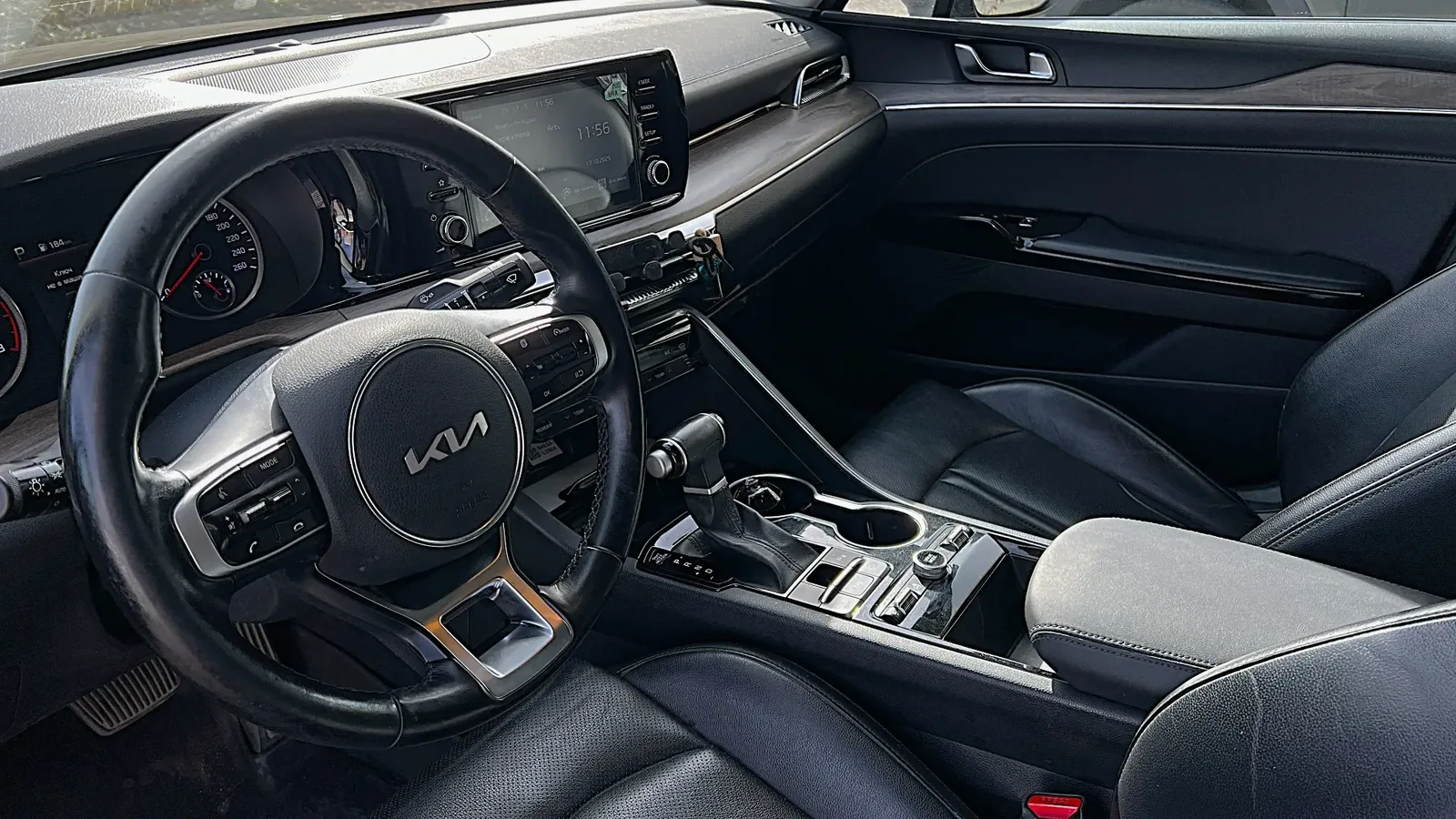 Передняя часть салона KIA K5 с рулём и мультимедийным экраном перед междугородней поездкой из Астаны в Караганду