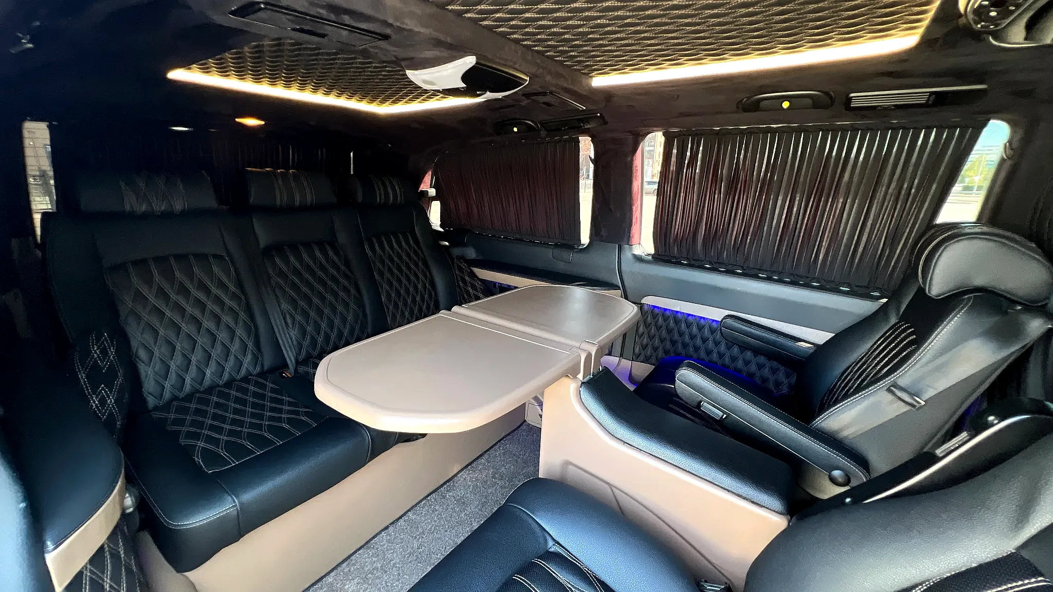 Зона отдыха в Mercedes-Benz Viano с овальным столом и диванами, удобная для суточной аренды минивэна