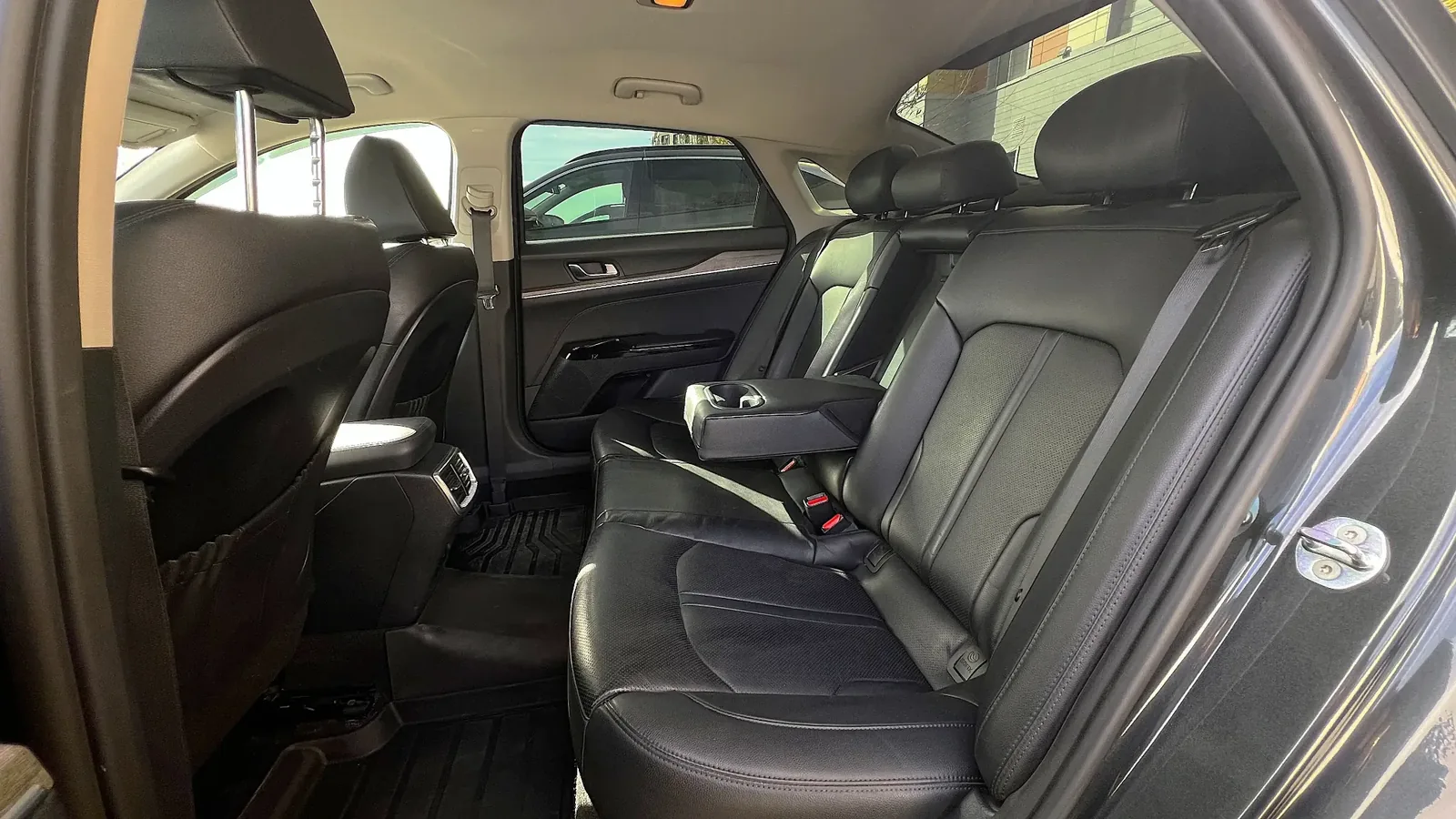 Задний ряд кожаных сидений KIA K5 с центральным подлокотником на трёх пассажиров, подготовленный к поездке с водителем из Астаны в Алматы